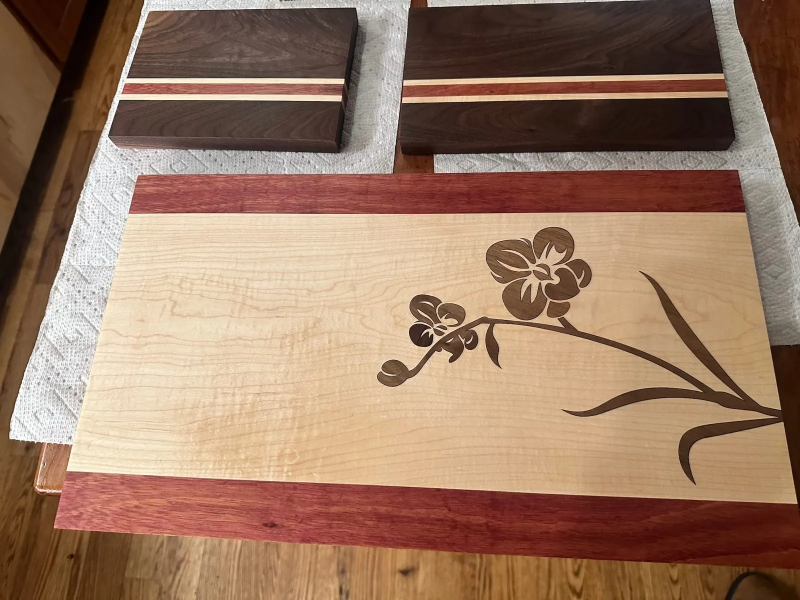 Various cutting boards including a large laser-cut inlay with walnut, maple, and purple heart